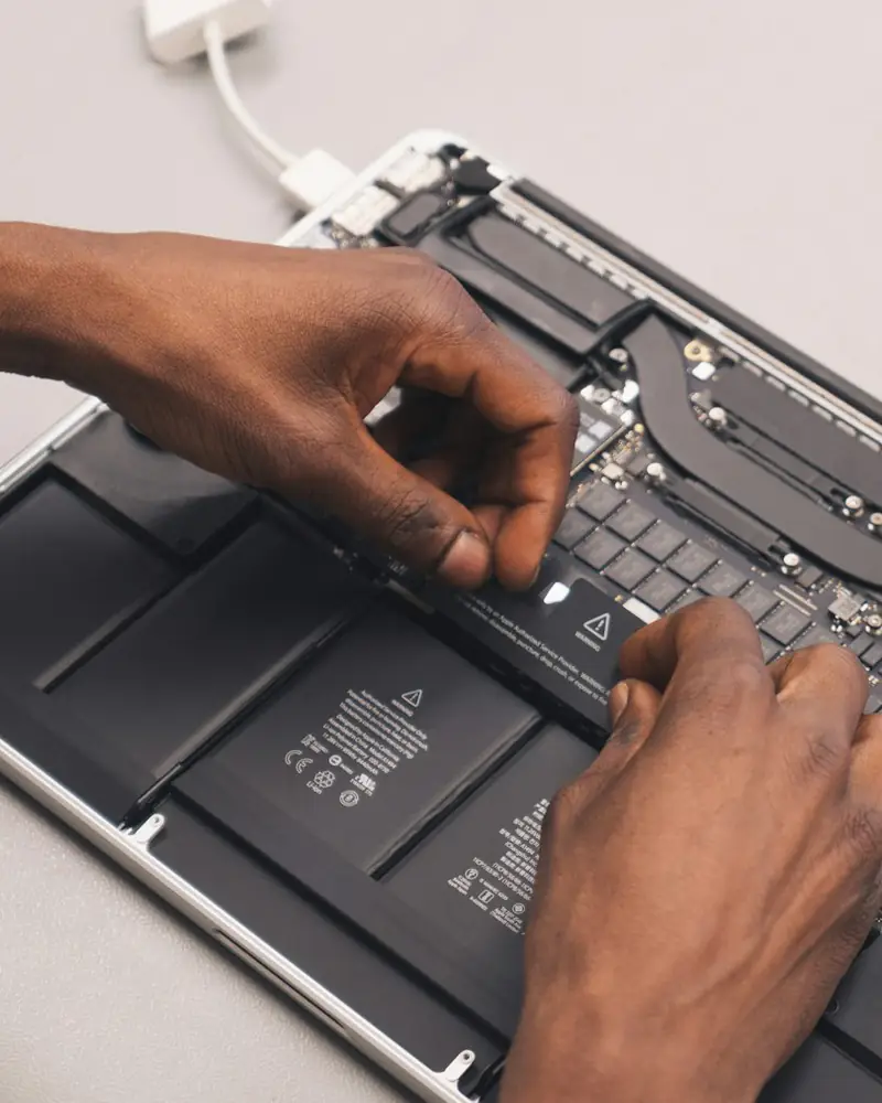 Mains d’un technicien qui intervient sur un ordinateur portable ouvert